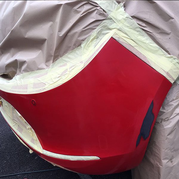 Masked red bumper part way through a mobile SMART repair