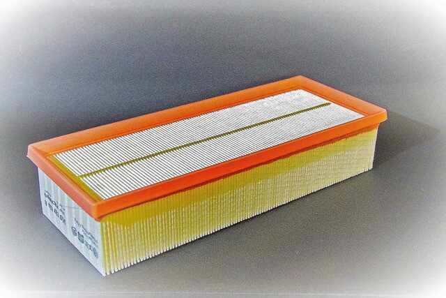 A car engine air filter element sitting on a workbench