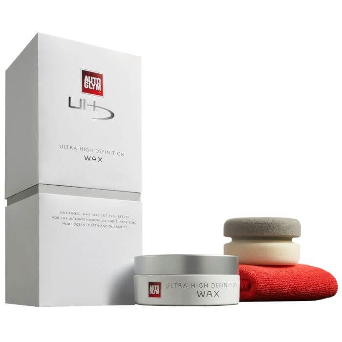 A tin of Autoglym high definition car wax next to its applicator on a clean panel