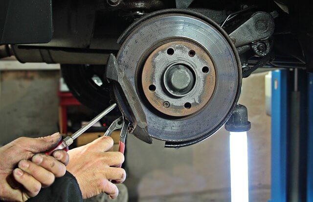 A car raised on a workshop ramp with the wheel removed and the brake disc and hub exposed