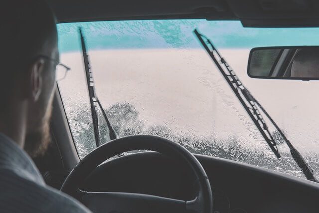 Windscreen wiper blades clearing a car windscreen in winter conditions