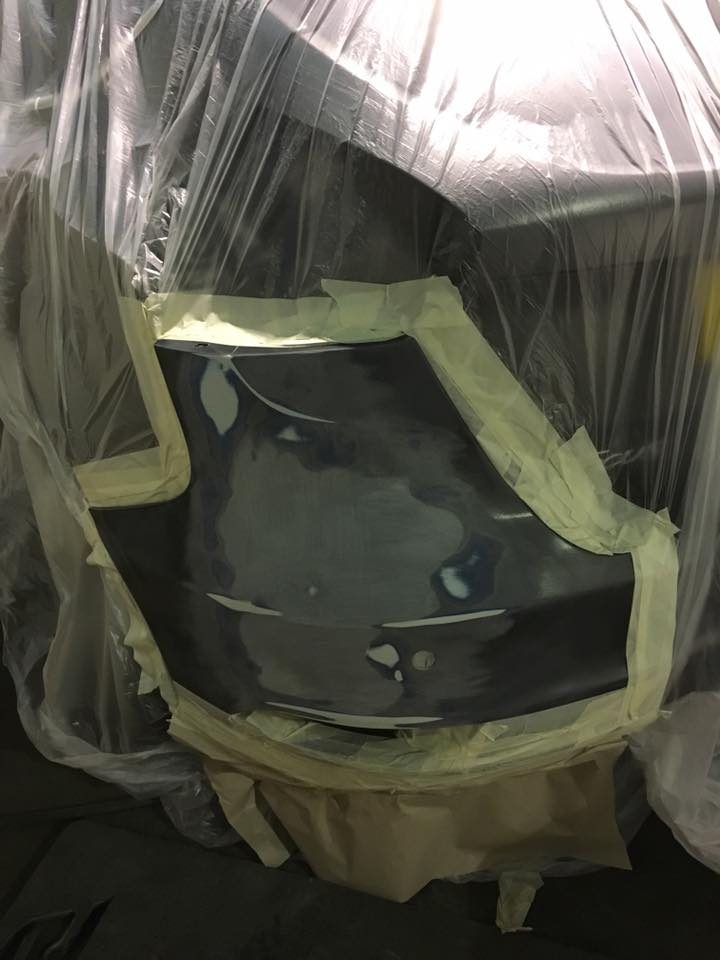 A car body panel being worked on during a paint repair with the surrounding area masked
