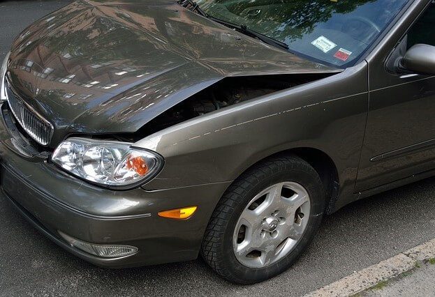 The front wing and bonnet of a saloon car creased and dented after a collision