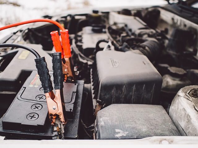 Red and black jumper cables clipped onto a car battery terminal