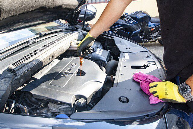 A mechanic draining used engine oil from a car during a service