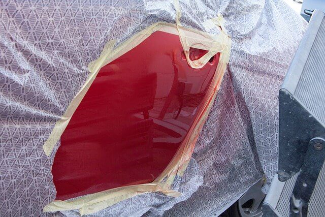 Technician spraying paint onto a car panel in a body shop