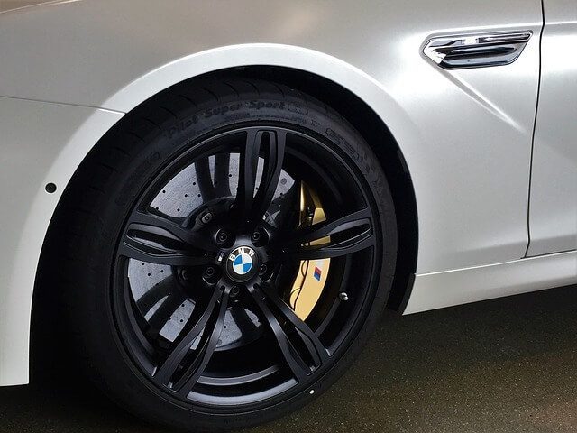 Black painted alloy wheels fitted to a parked car, photographed from the side