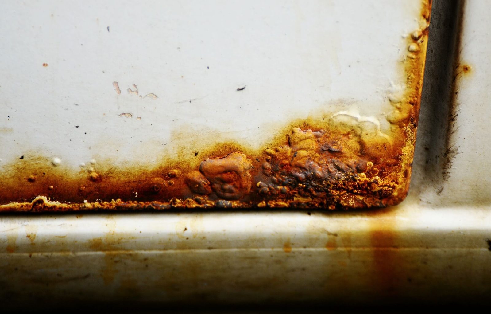 Rust and bubbling paint along the bottom edge of a car door